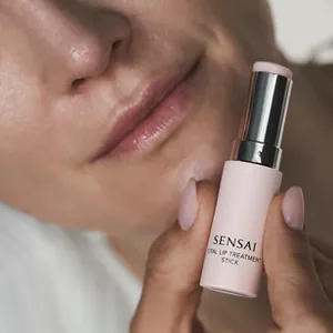 Close up of person's lips while holding Total Lip Treatment Stick in hand